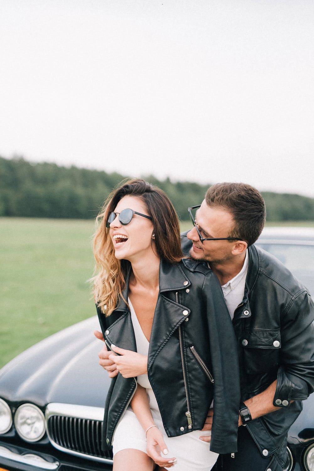 a man and woman kissing in front of a car